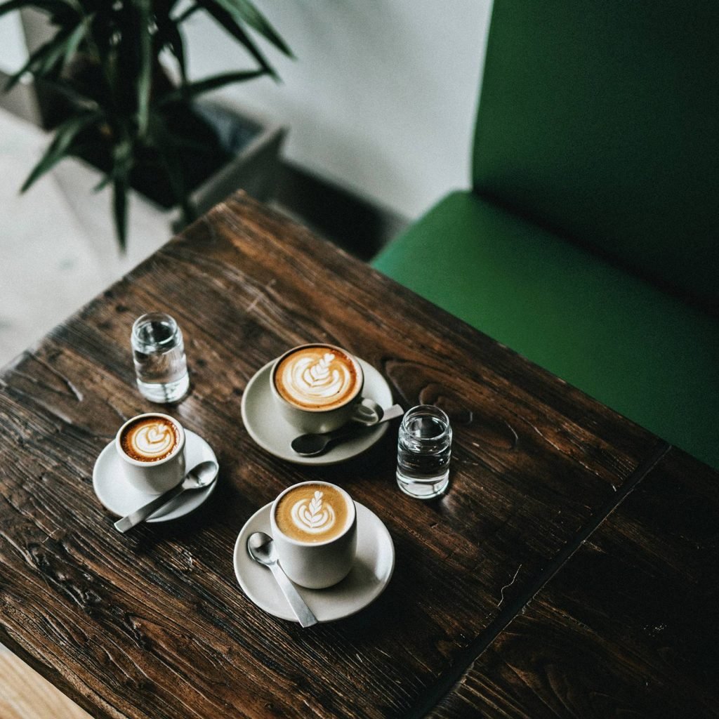 Tres cafés con arte latte sobre una mesa de madera